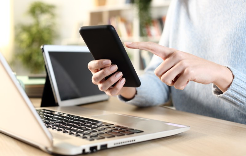 Como é calculada a Taxa do valor do condomínio | Foto de uma pessoa olhando para o celular na frente de um computador | Estilo de Vida | Blog Alea
