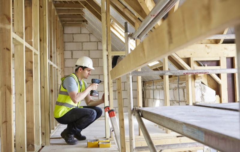 Casa wood frame | Foto de um homem consertando uma estrutura de madeira de uma casa | Método Construtivo | Blog Alea