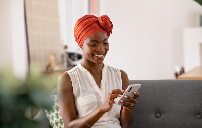 Mulher sorrindo mexendo no celular | Dicas para facilitar a comprovação de renda | Tudo sobre Casa Verde e Amarela | Blog Alea