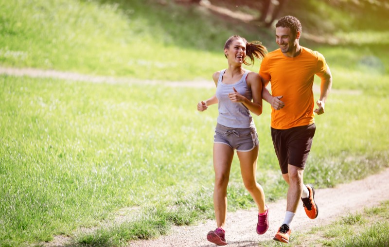 Homem e mulher fazendo caminhada em um parque | Vantagens de morar em condomínio | Como comprar uma casa | Blog Alea
