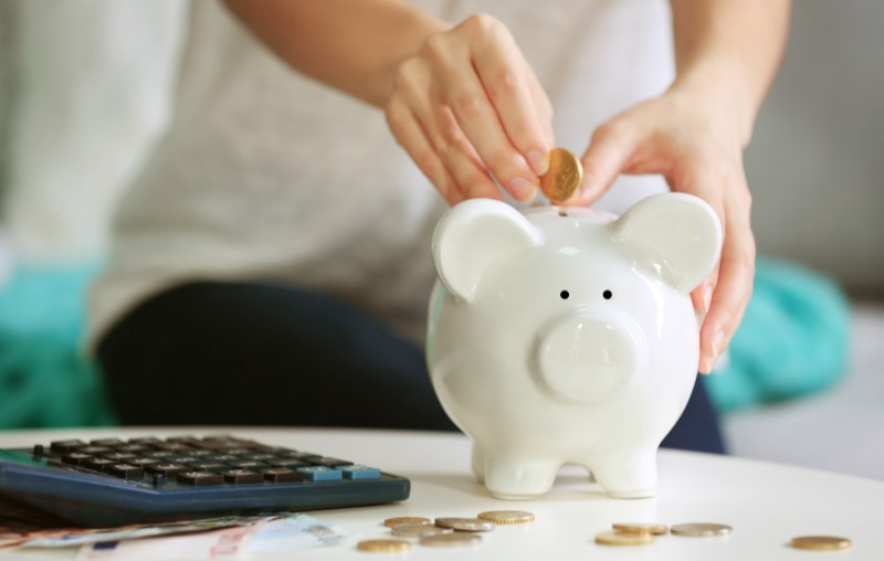 Foto de uma Mão feminina colocando moedas em um cofrinho | O que é subsídio? | Tudo sobre Casa Verde e Amarela | Blog Alea