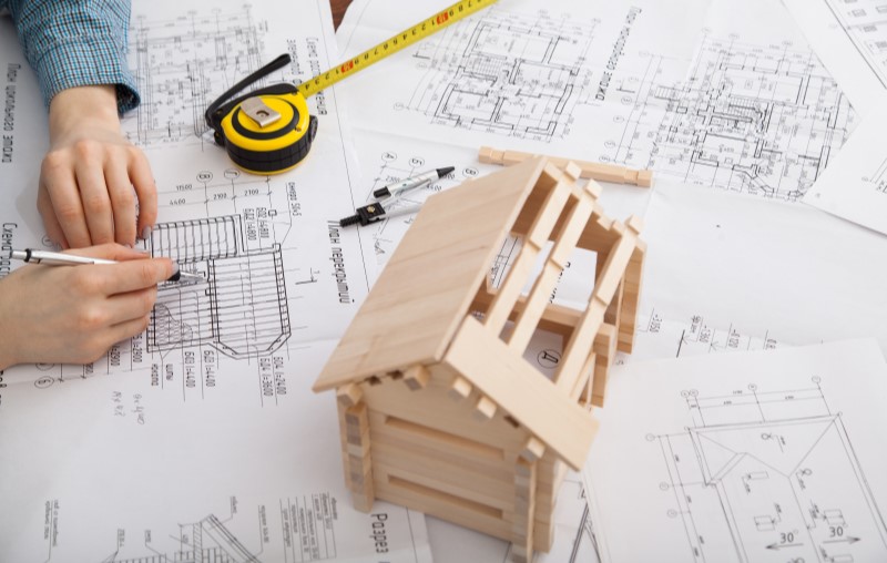 Miniatura de casa de madeira sob plantas | O que é uma casa pré-fabricada | Método Construtivo | Blog Alea
