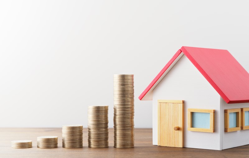 Como funciona um financiamento | Miniatura de uma casa e moedas empilhadas | Como comprar uma casa | Blog Alea