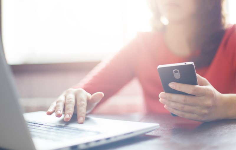 Diferença entre valor de entrada e valor do imóvel | Mulher segurando um celular fazendo uma pesquisa no computador | Como comprar uma casa | Blog Alea