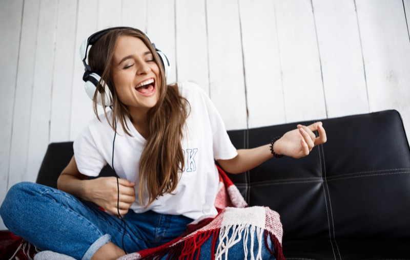 O que é a lei do silêncio em condomínios | Jovem mulher escutando música em casa | Estilo de vida | Blog Alea