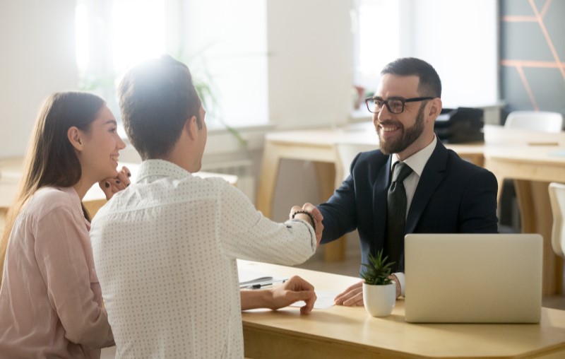 Etapas do financiamento imobiliário | Casal fechando contrato com o corretor de imóveis | Como comprar uma casa | Blog Alea