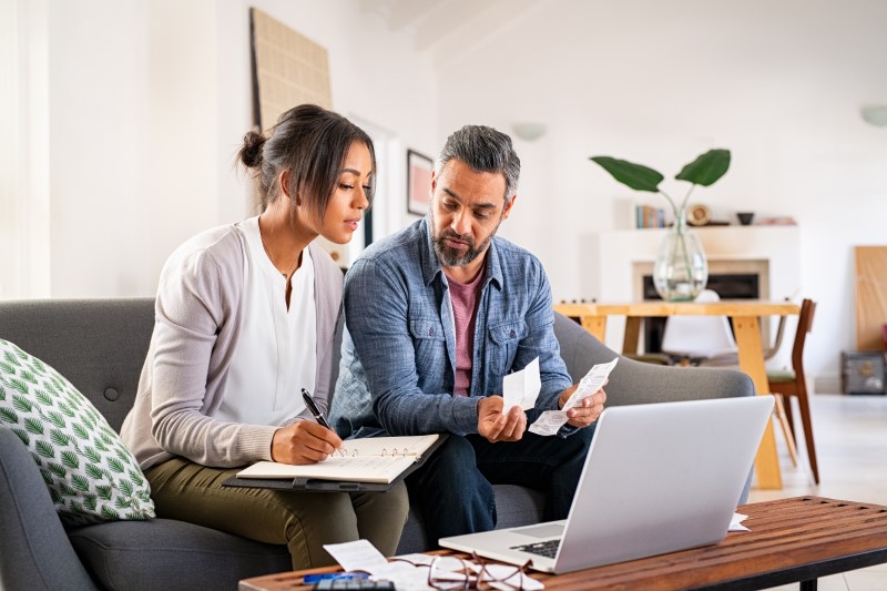 Quem é isento no Imposto Predial | Foto de um casal fazendo as contas e olhando para o computador | Como comprar uma casa | Blog Alea