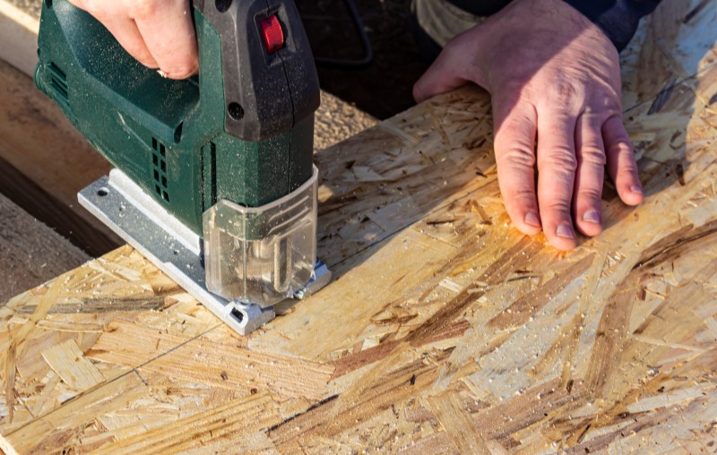 Alvenaria x Wood Frame | Foto de um engenheiro manuseando uma placa de OSB | Método Construtivo | Blog Alea