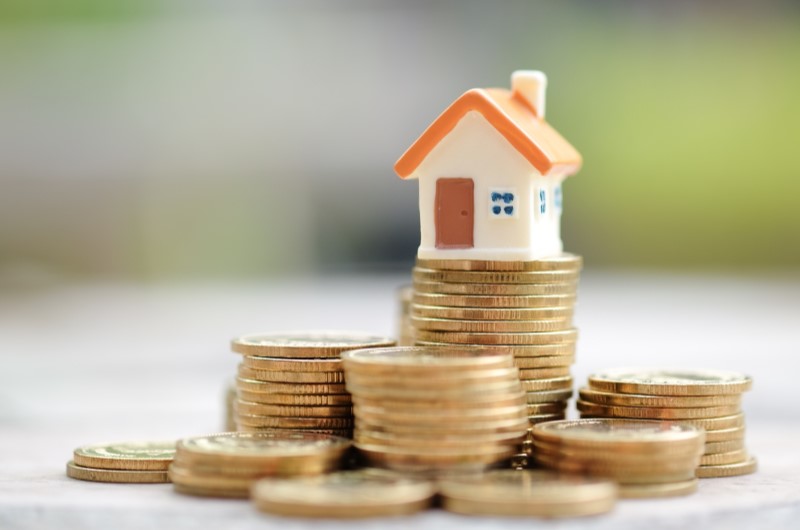 Como funciona o subsídio Minha Casa Minha Vida | Foto de diversas moedas espalhadas, com uma miniatura de casinha no topo | Tudo sobre Minha Casa Minha Vida | Blog da Alea