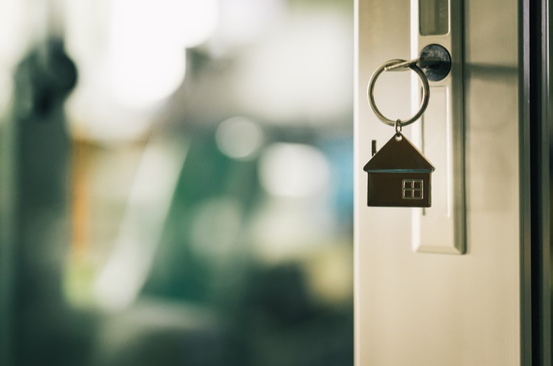 Como funciona o programa Minha Casa Minha Vida? | Foto de uma porta entre aberta com um chaveiro de casa na porta | Tudo sobre Minha Casa Minha Vida | Blog Alea