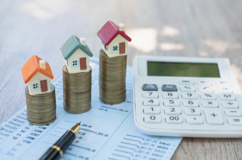 Junte o valor da entrada | Foto de uma calculadora ao lado de moedas e miniaturas de casinhas | Blog Alea