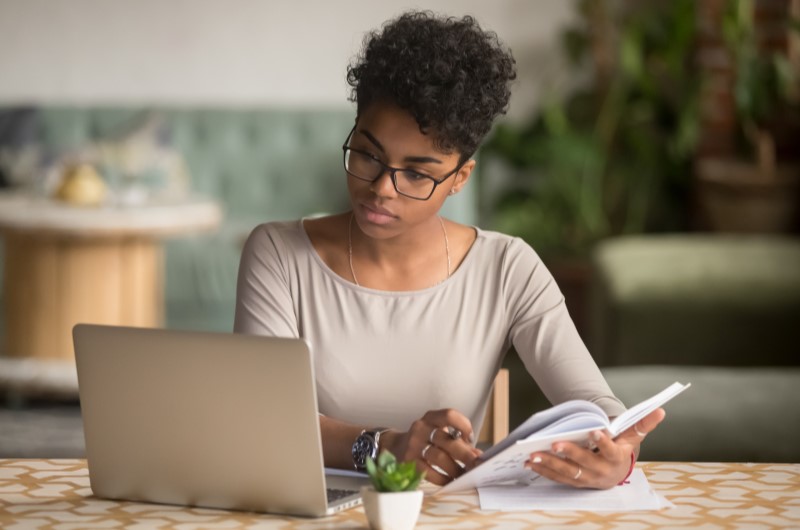 Avaliar o imóvel | Foto de uma mulher concentrada no notebook e segurando um papel | Como comprar uma casa | Blog Alea