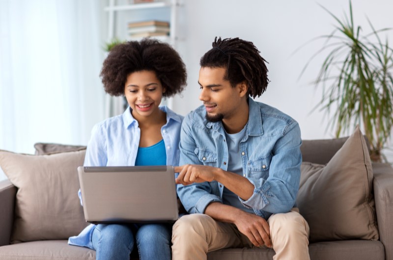 O que é financiar? | Foto de um casal na sala, usando o notebook | Como comprar uma casa | Blog Alea