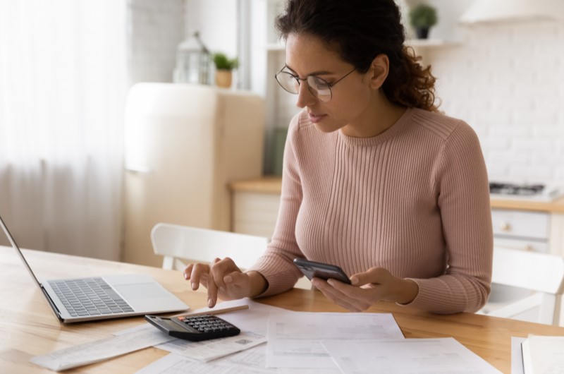 Quanto custa uma escritura de imóvel? | Foto de uma moça concentrada enquanto usa a calculadora | Como comprar uma casa | Blog Alea