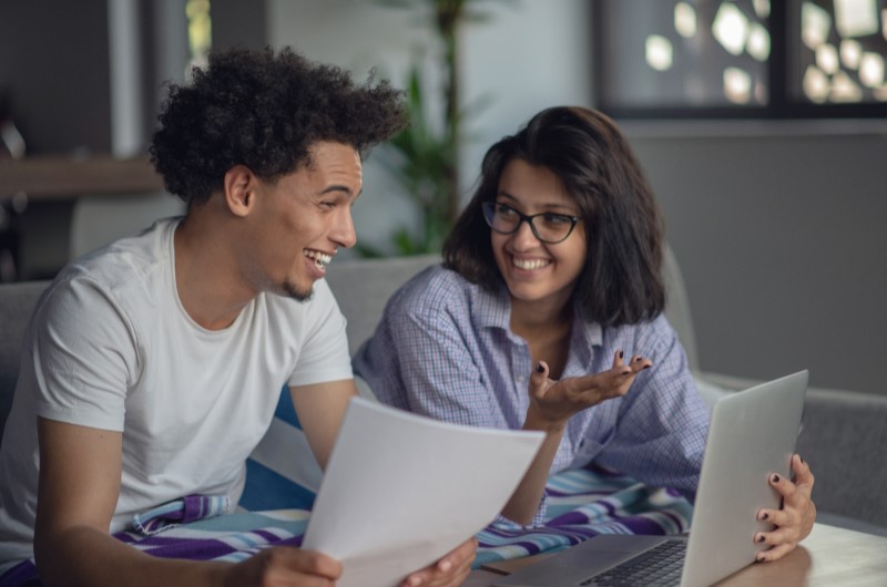 Quem pode participar do Minha Casa, Minha Vida? | Foto de duas pessoas sorridentes conversando na frente do notebook | Tudo sobre o Minha Casa Minha Vida | Blog Alea