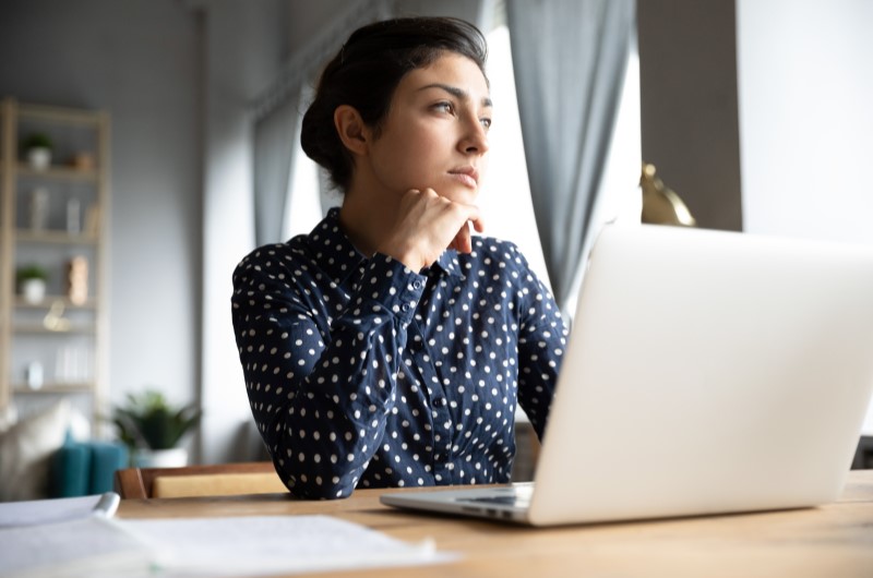 Comprar ou alugar uma casa qual a melhor opção | Foto de uma moça pensativa na frente do notebook | Como comprar uma casa | Blog da Alea